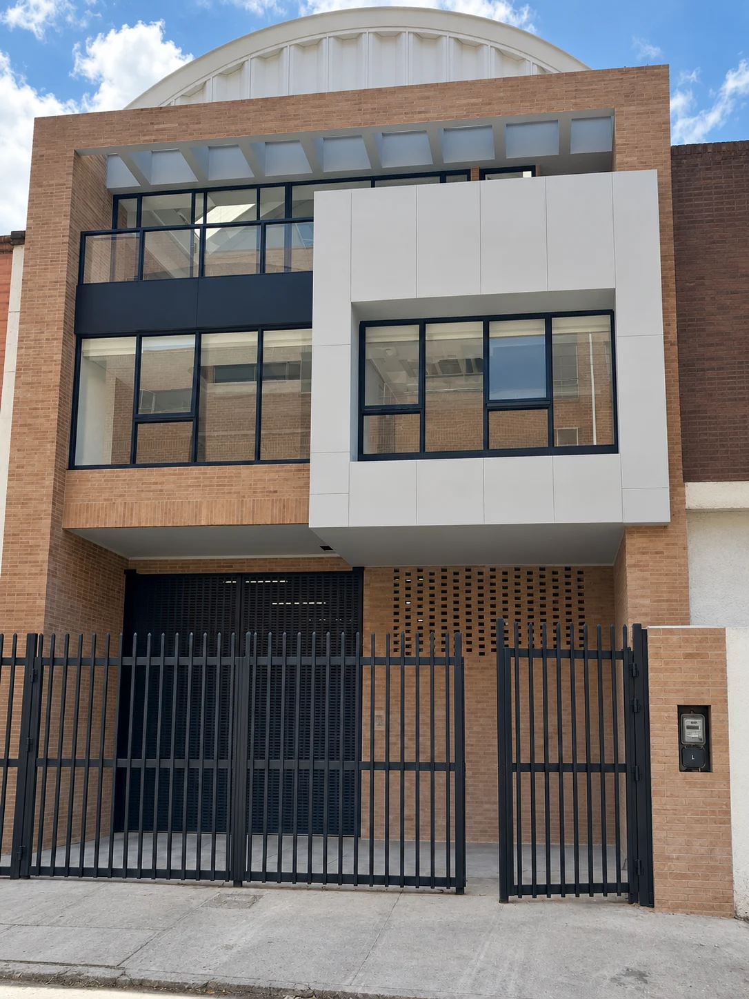 Maxicassa – fachada frontal con volumen en voladizo, ladrillo y celosía, Bogotá